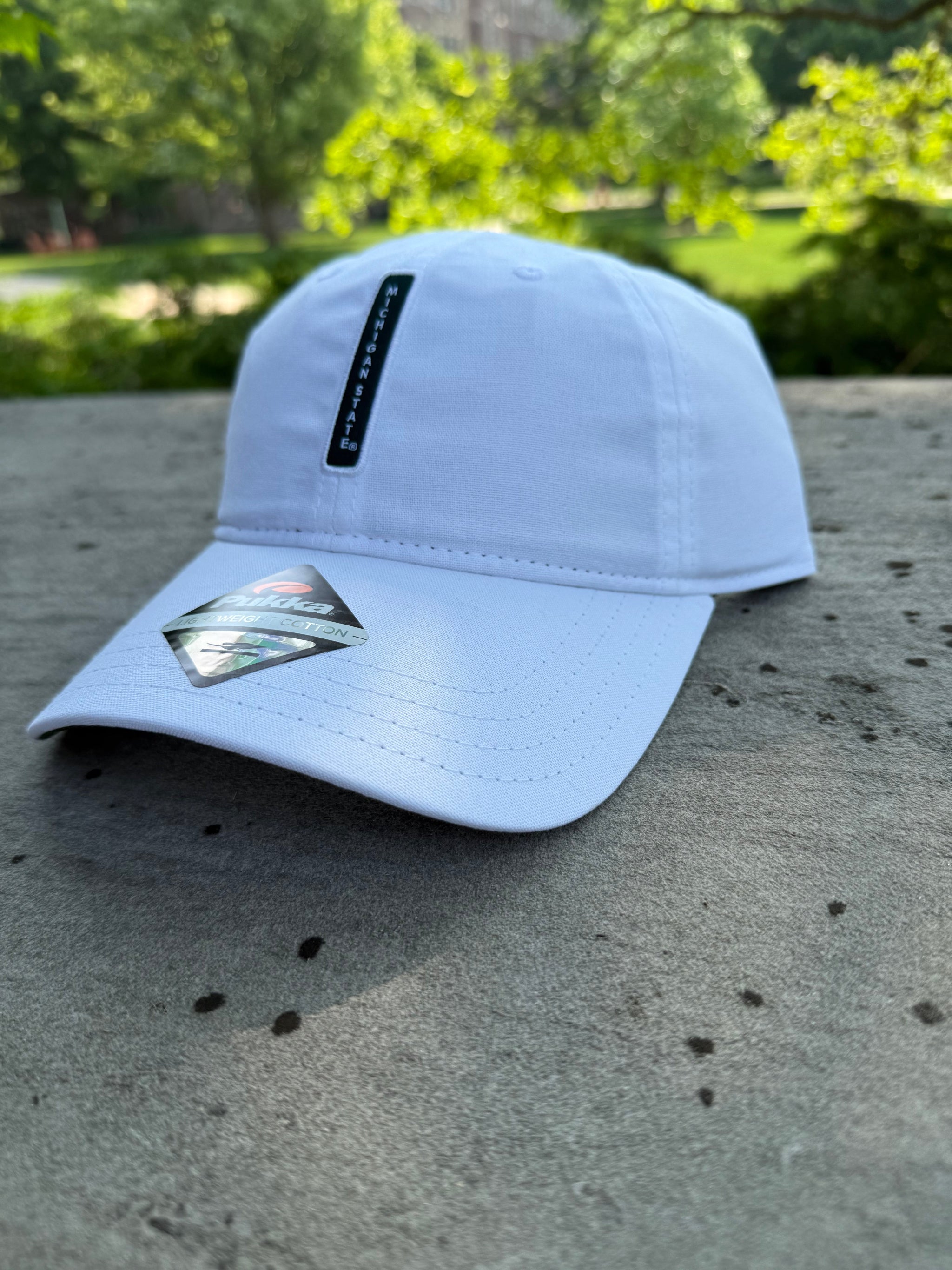 White hat with green vertical box with the words 'Michigan State' in white on the front.
