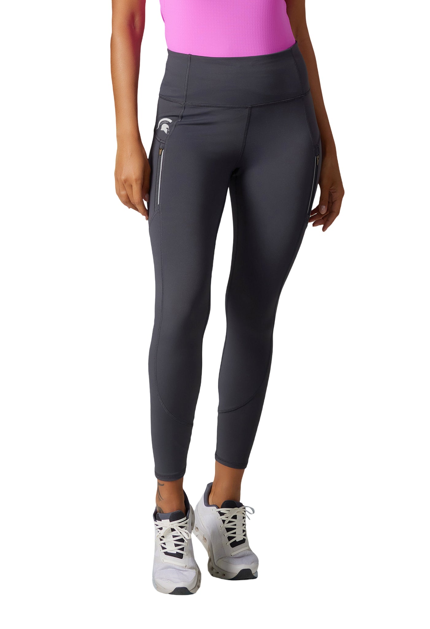 Person wearing a pink top, dark gray high-waisted leggings with a white Spartan helmet above the left zipper pocket, and white sneakers