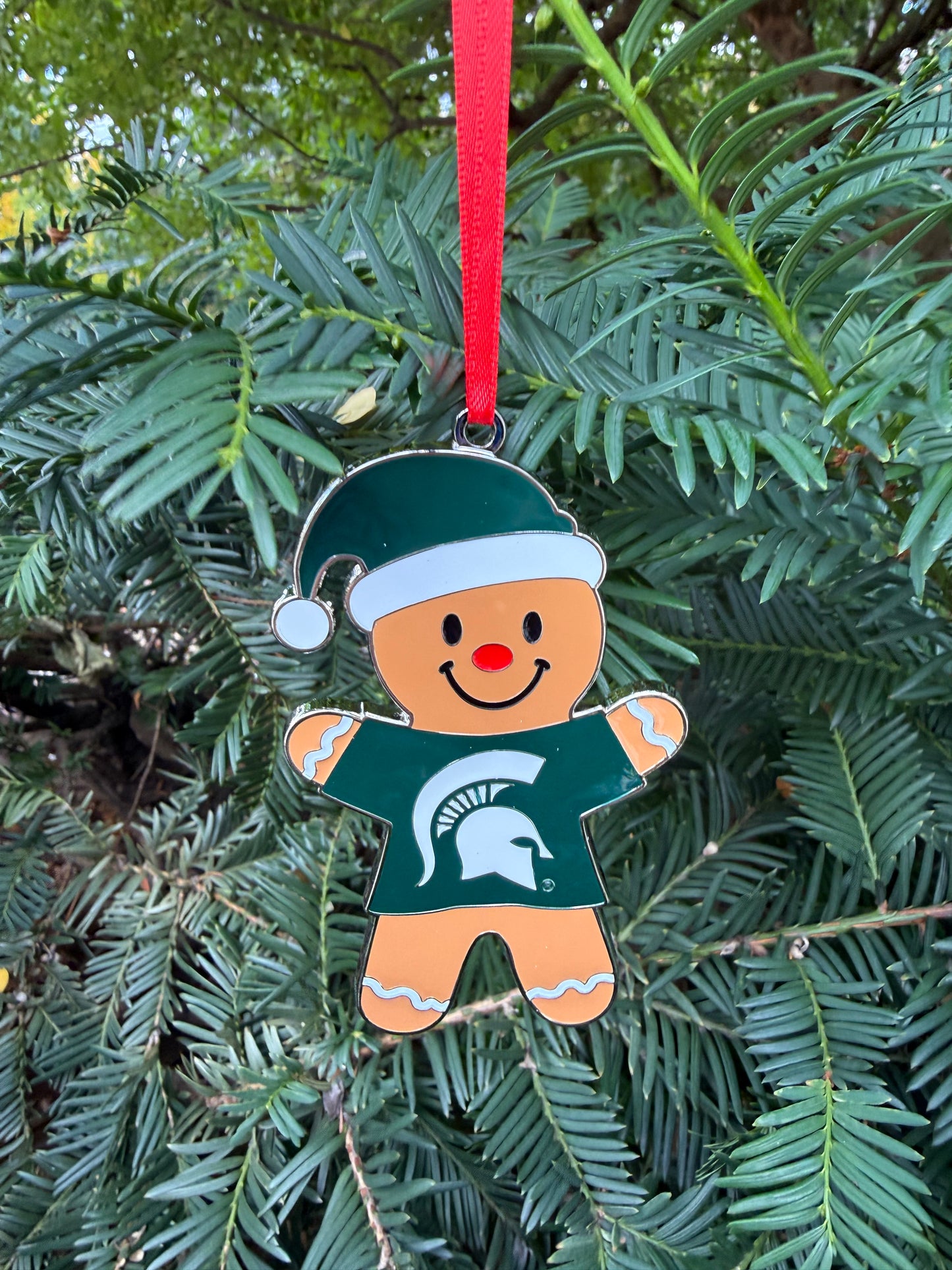 Decorative gingerbread man ornament with a green and white festive hat on and green T-shirt with a white Spartan helmet logo on the front.
