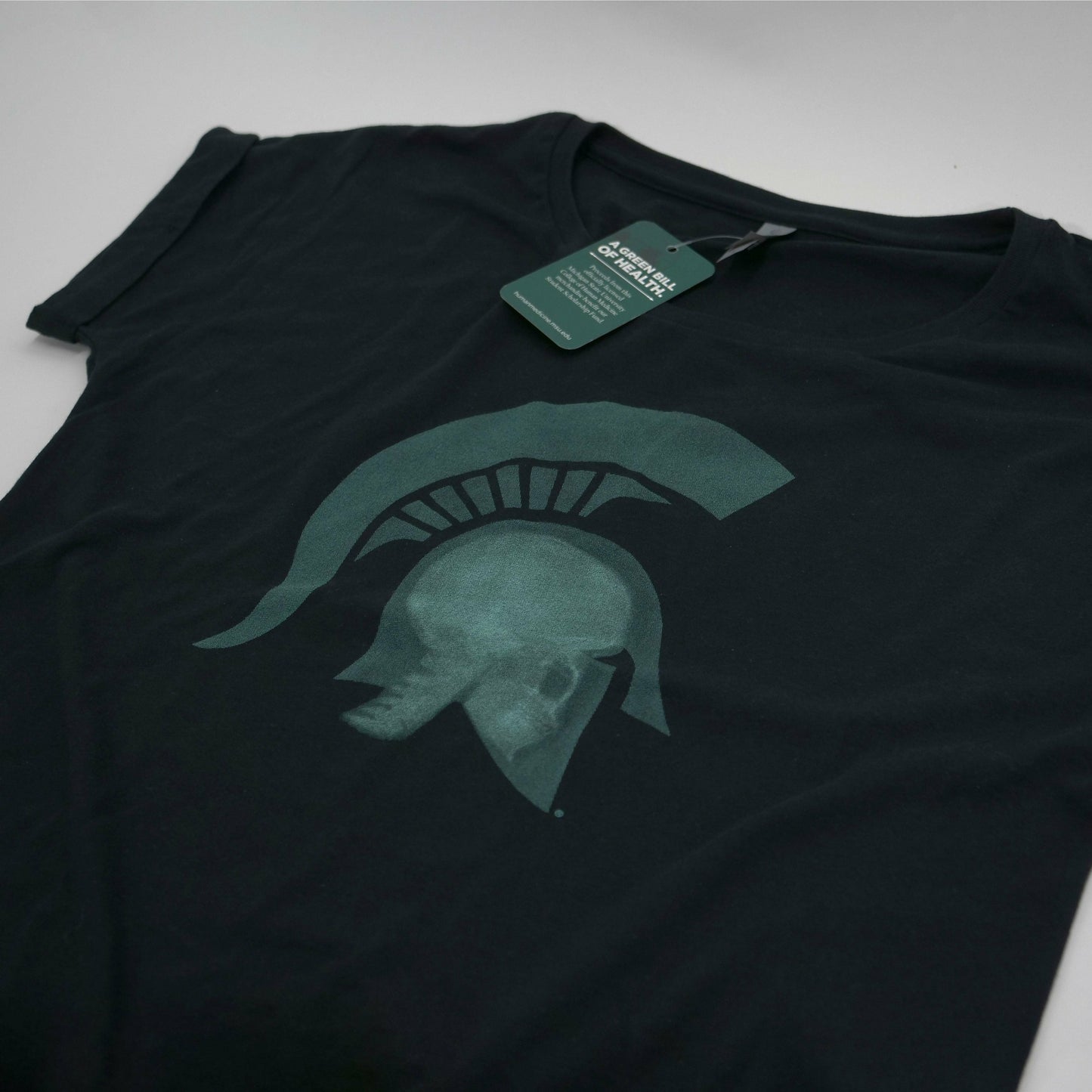 Flat angled view of black short sleeve scoop neck T-shirt with a graphic of a head wearing a Spartan helmet being x-rayed.