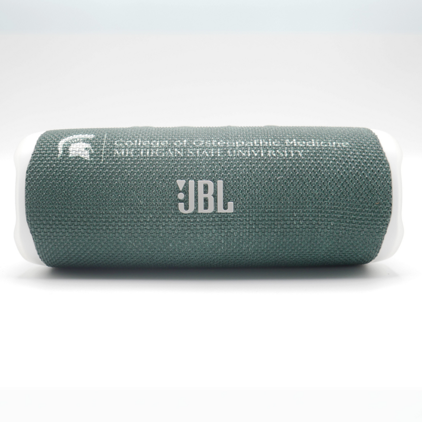 A dark green JBL Flip 6 bluetooth speaker with the MSU College of Osteopathic Medicine logo in gray above the gray JBL logo.