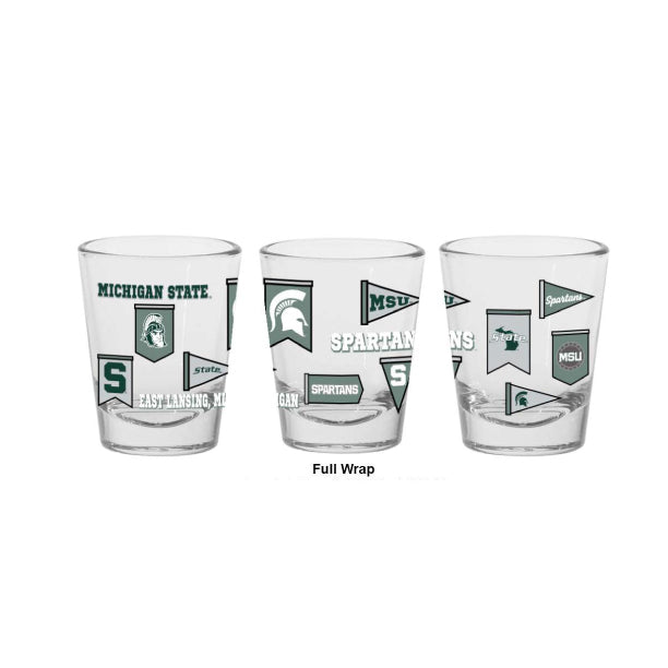 Clear glass Michigan State Spartans shot glass featuring a full-wrap design with multiple team graphics, including the Spartan helmet logo, block "S," Michigan State wordmark, pennant-style banners, "Spartans" text, "MSU," "State," and "East Lansing, MI." Product is shown from three angles to display the complete wraparound design on a light gray background.