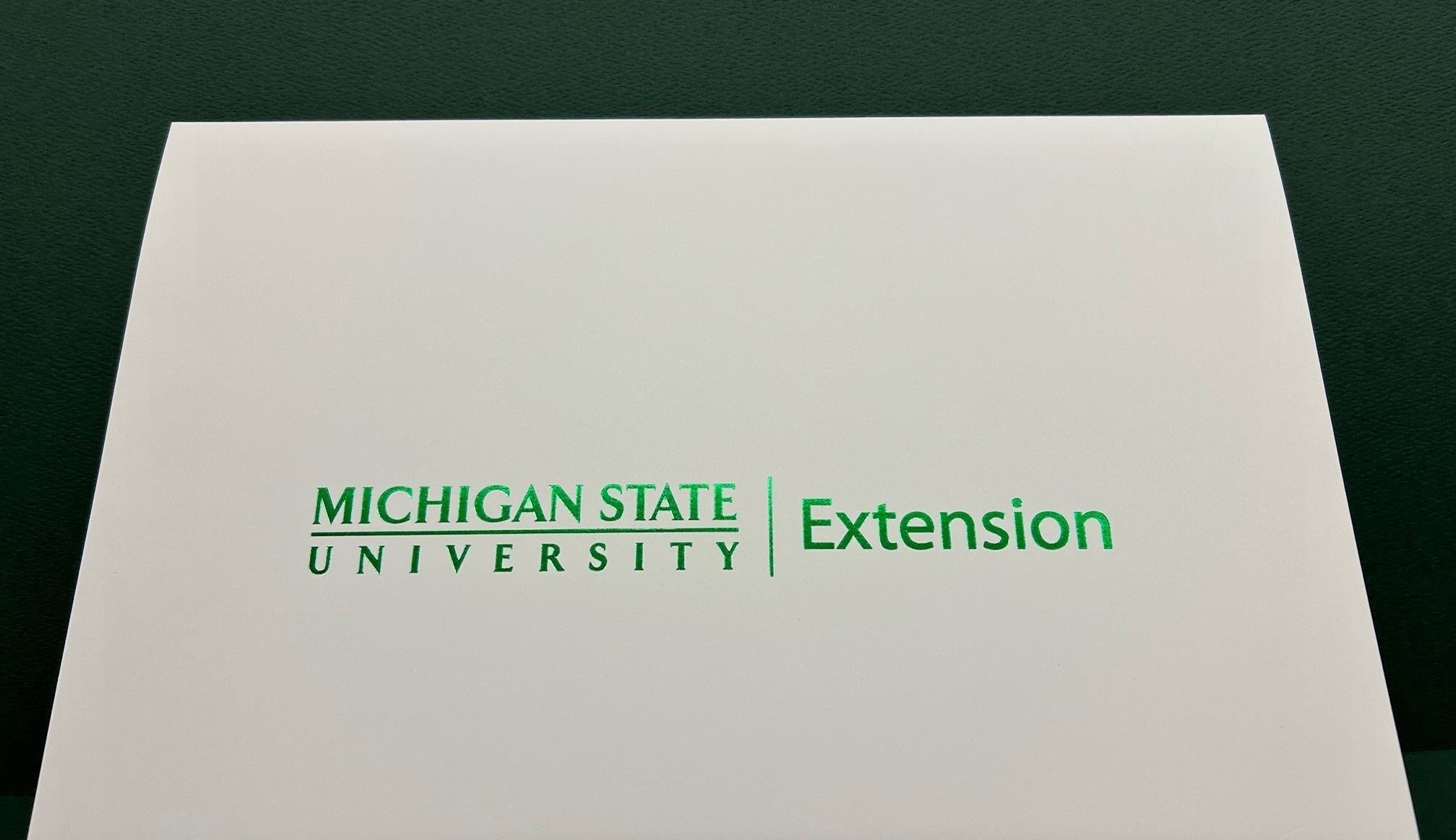 Front side of a certificate holder in white accompanied by the MSU Extension signature in Spartan green.