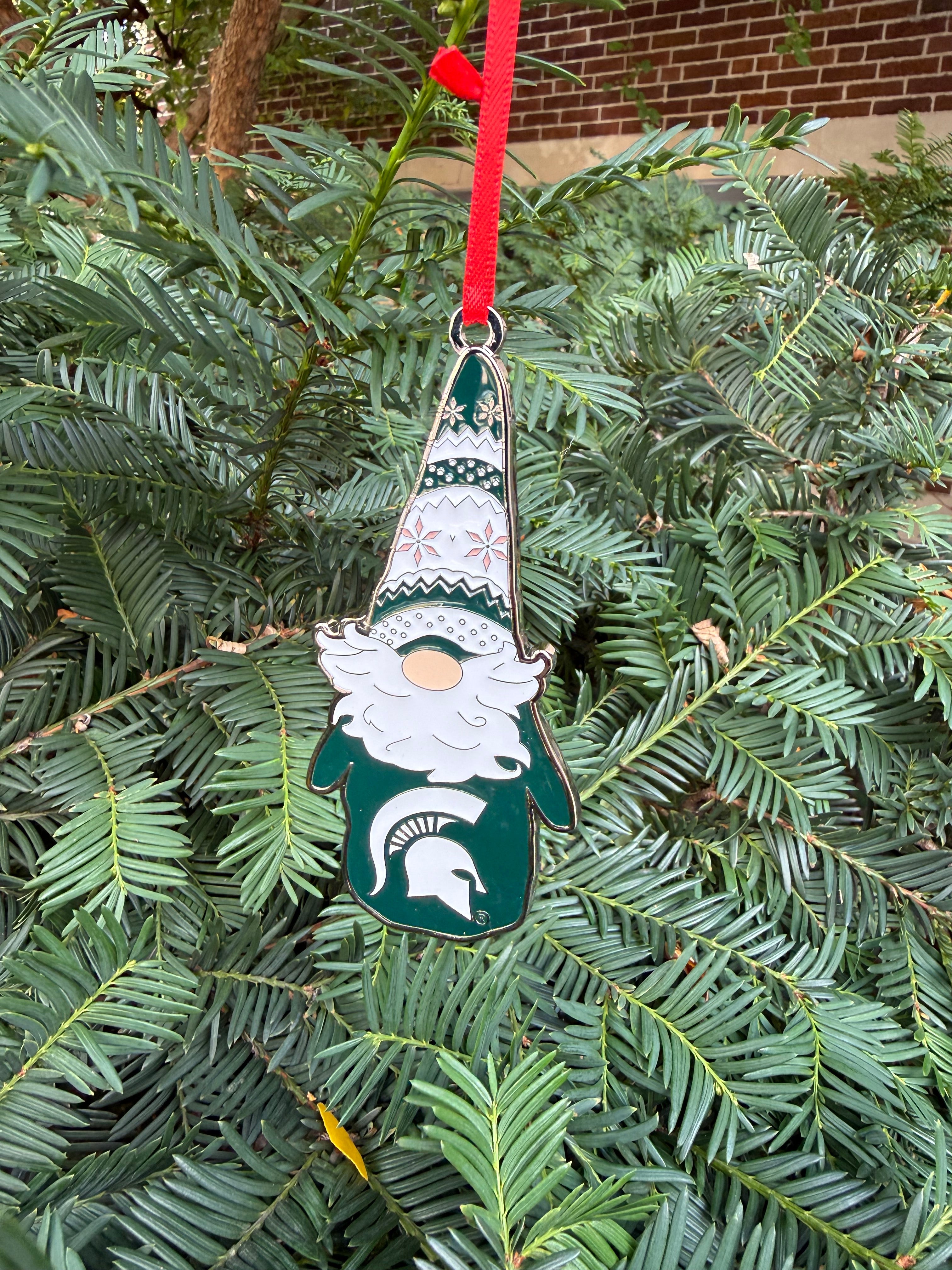 Decorative green and white gnome ornament. The gnome has a green and white hat with festive designs on it. The gnome's green sweater has a white Spartan helmet logo on the front.
