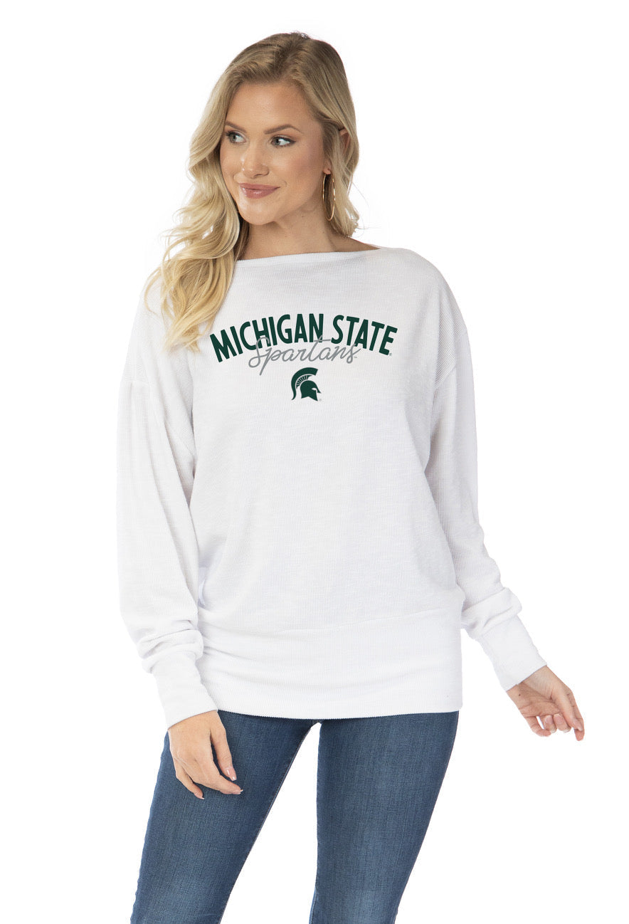 A model wearing a white ribbed top that reads "Michigan State Spartans" in green and gray above a green Spartan Helmet logo.