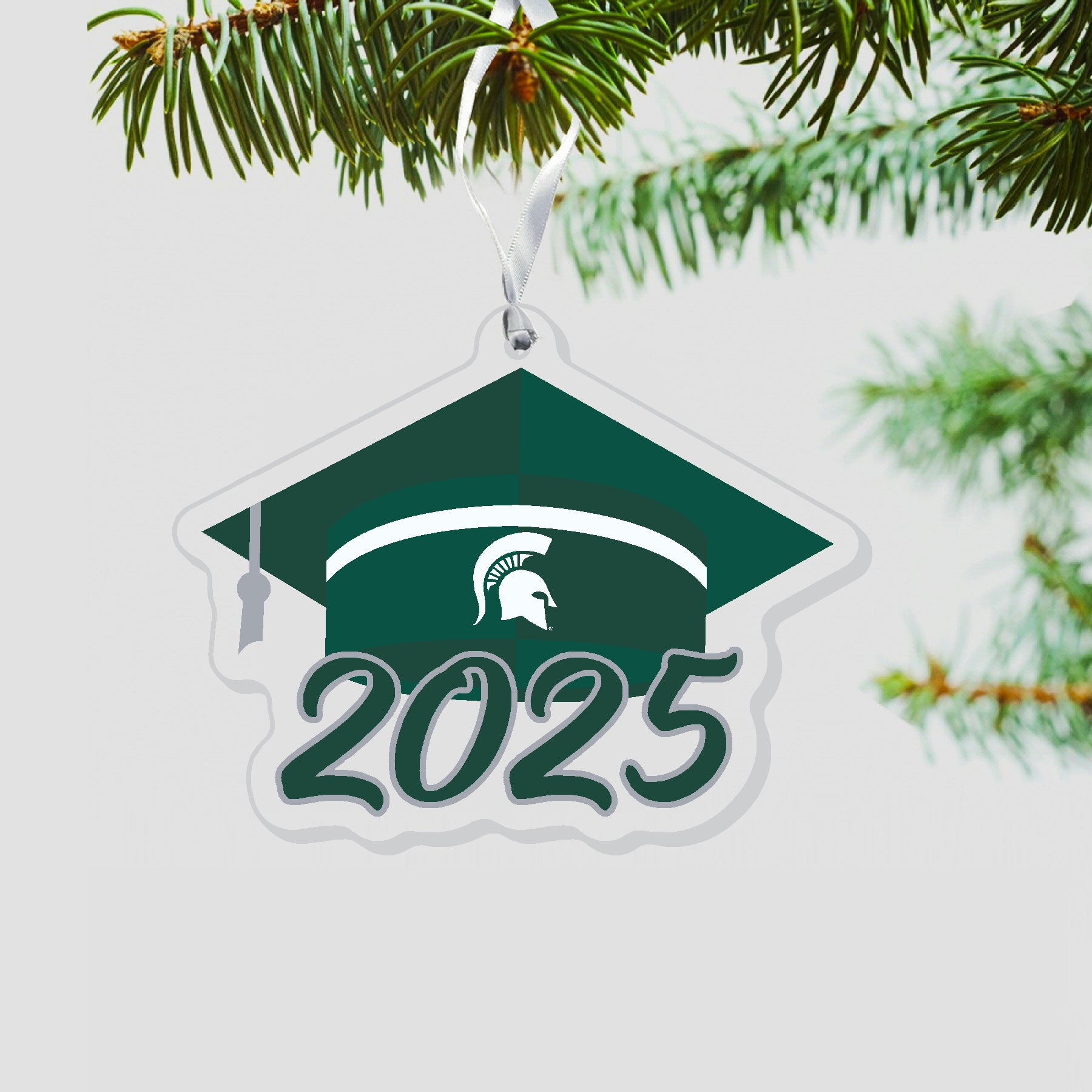 Graduation cap ornament with a white stripe at a base of the cap. White Spartan helmet centered on green band. 2025 is under the cap in green outlined in silver.