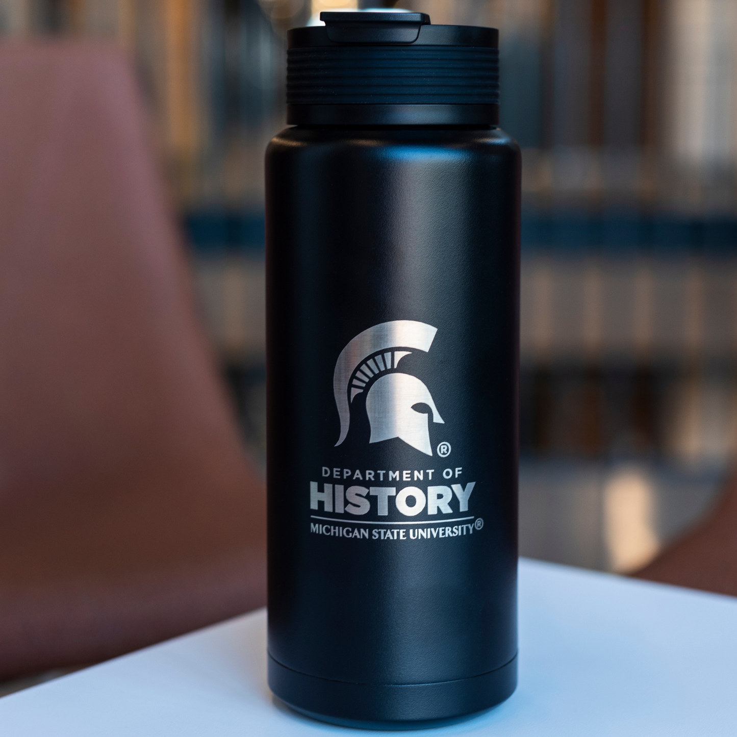 Black 34 ounce water bottle with a laser-etched design featuring a silver Department of History logo and Spartan Helmet logo.
