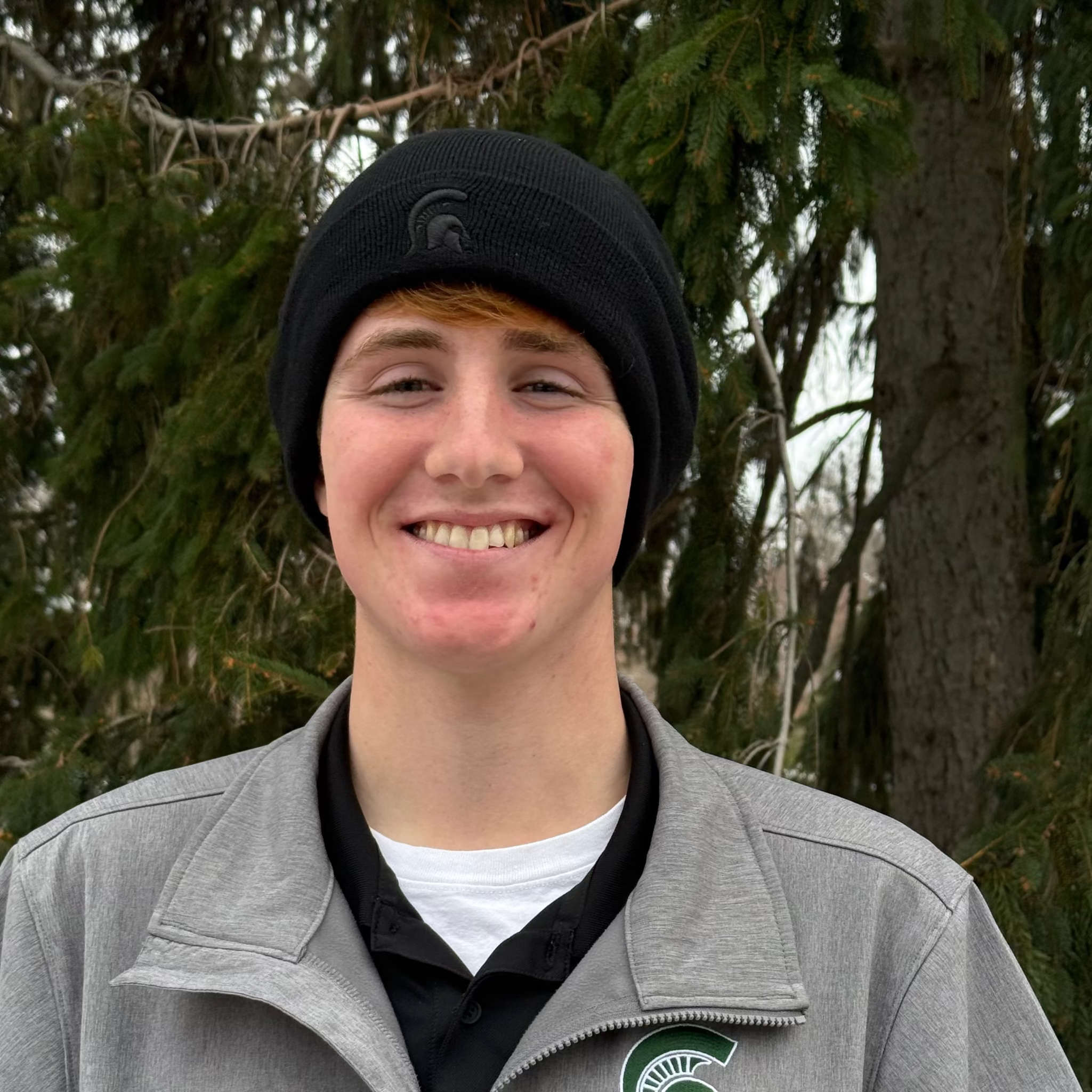 Person wearing a black cuffed knit beanie with a black embroidered Spartan Helmet logo centered on cuff.