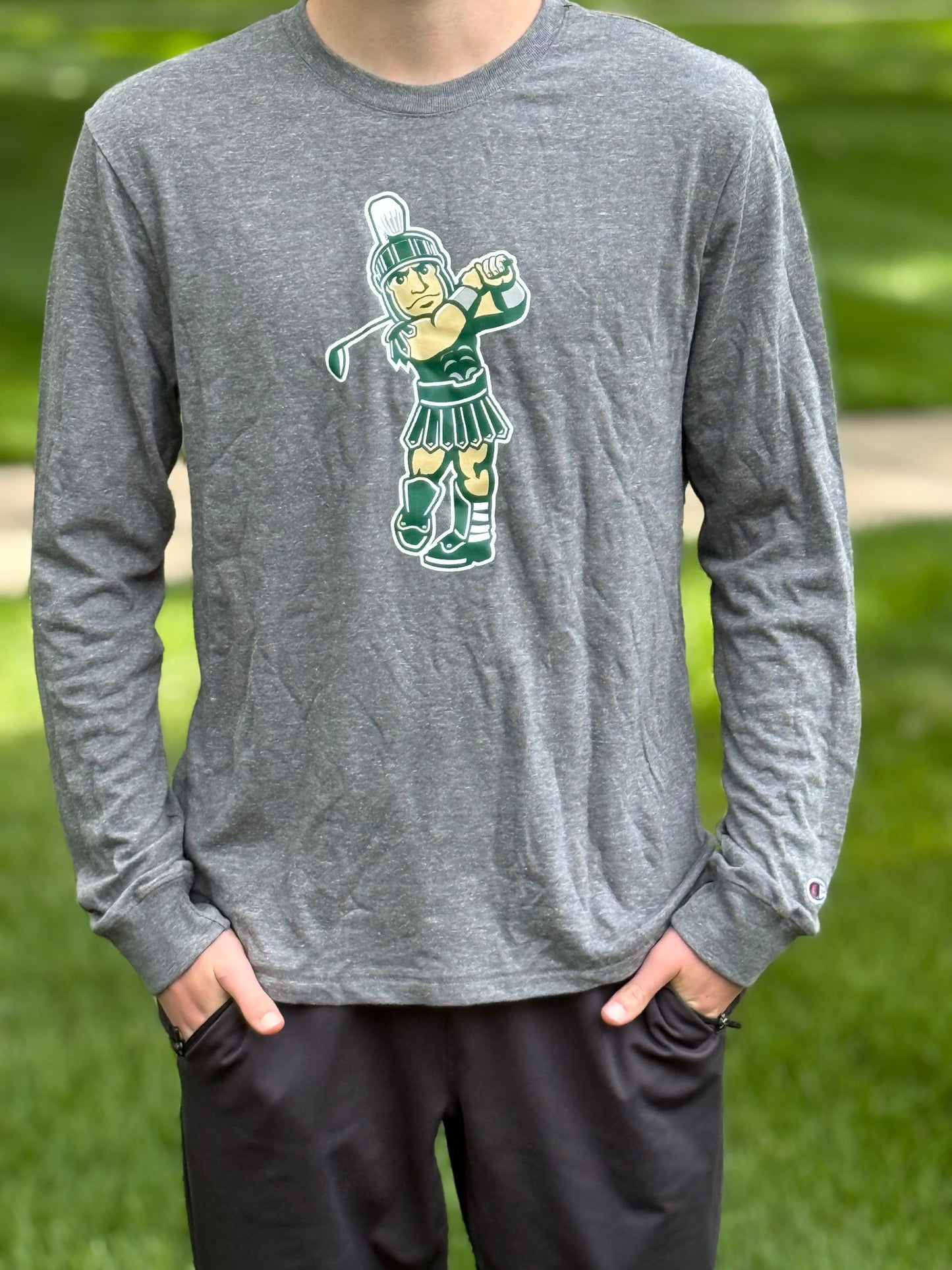 Person wearing a heather gray long-sleeve crewneck shirt featuring a Golf Sparty screen print graphic on the front.