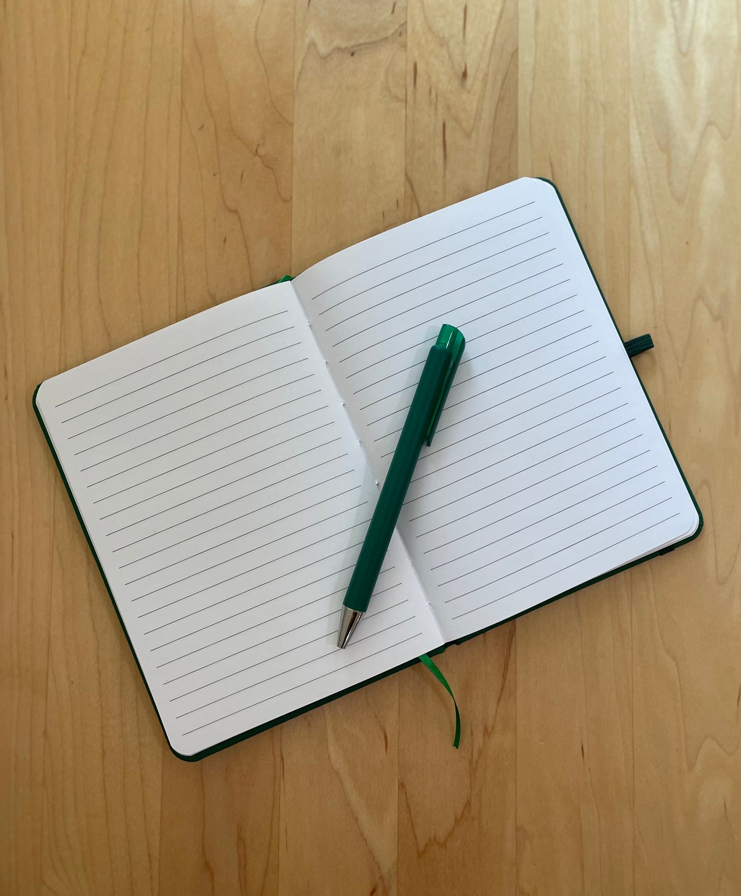Open notebook with lined pages and a green pen.