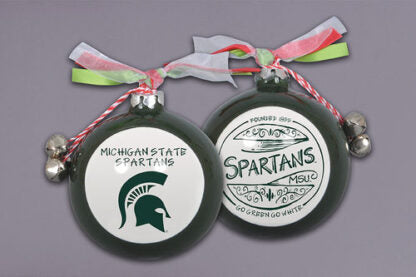 Two green Michigan State University Christmas ornaments with red, white, and green ribbons and silver bells. One features 'MICHIGAN STATE SPARTANS' with a Spartan helmet, and the other displays 'Founded 1855 SPARTANS MSU GO GREEN GO WHITE' in a decorative design.