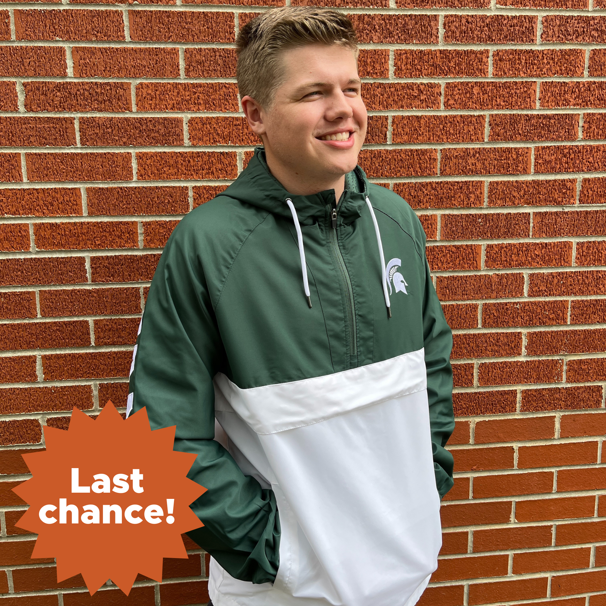 A person wearing a green and white hooded rain jacket. The jacket has the MSU spartan helmet logo in white on the left chest, with Spartans in all caps down the side of the right sleeve. In the lower left corner is an orange sunburst with the words "Last chance!"