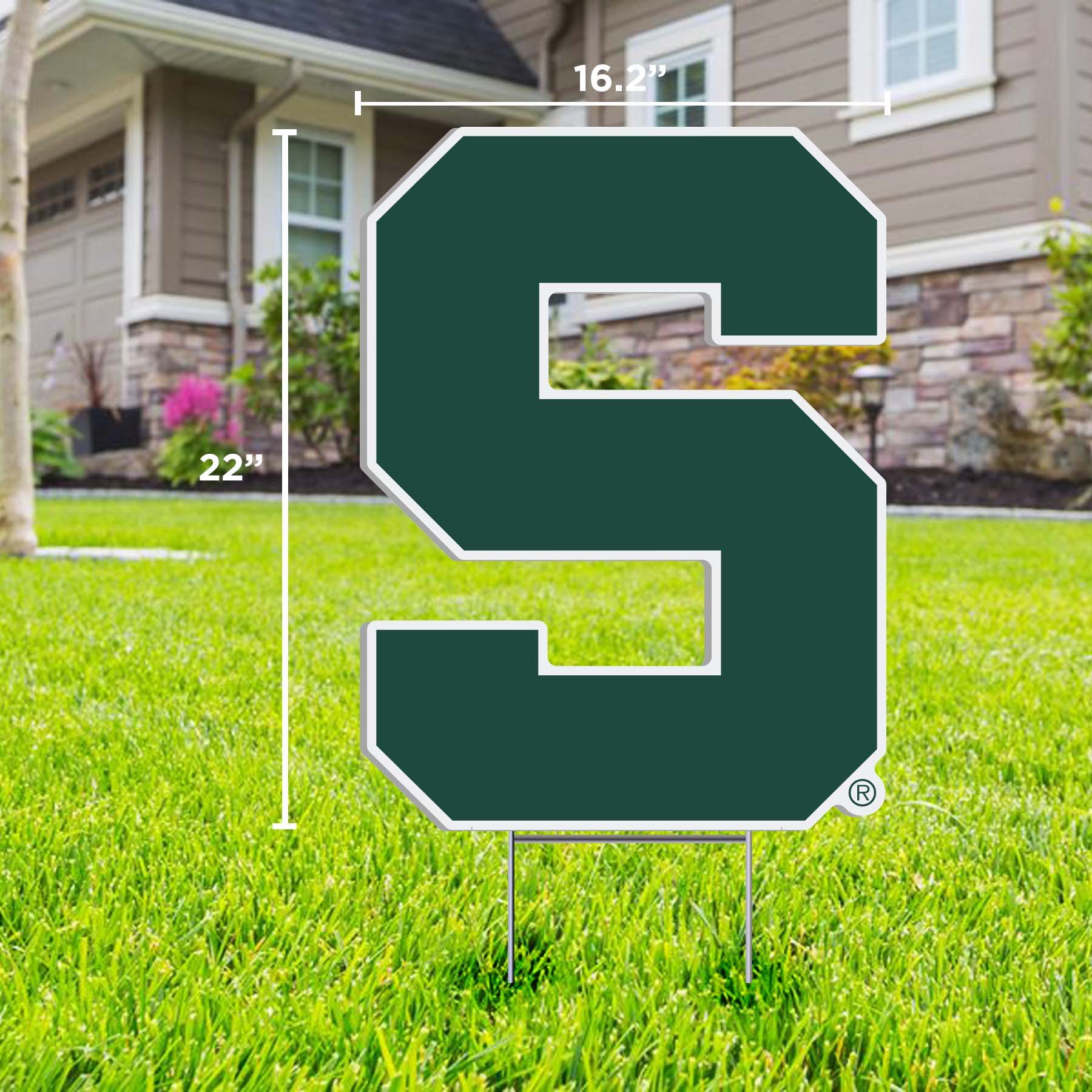 A lawn sign with a large letter 'S' in green outlined in white, representing Michigan State University, placed on a lawn.