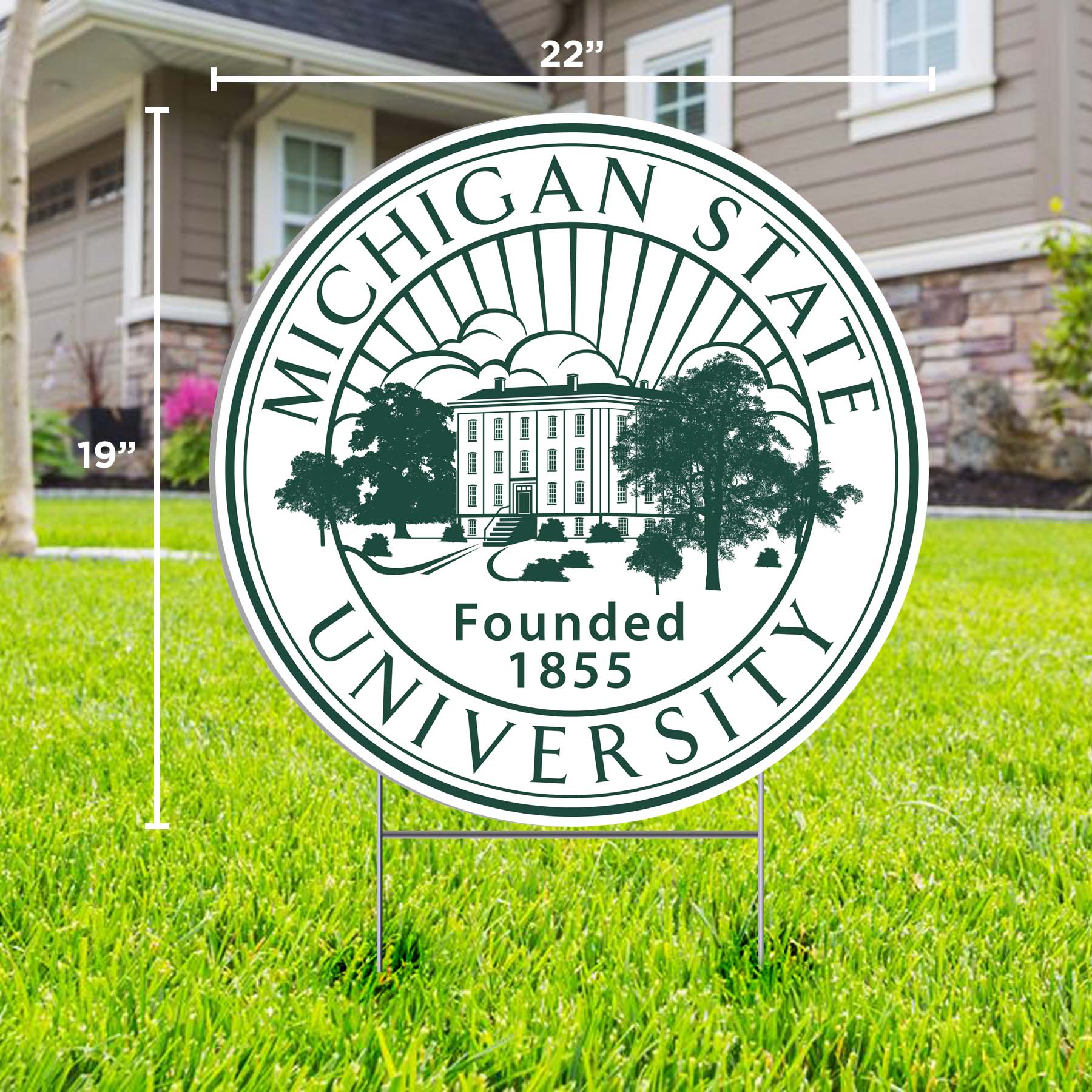 A circular lawn sign for Michigan State University with dimensions marked, displayed on a lawn, featuring the MSU seal and the founding year of 1855.