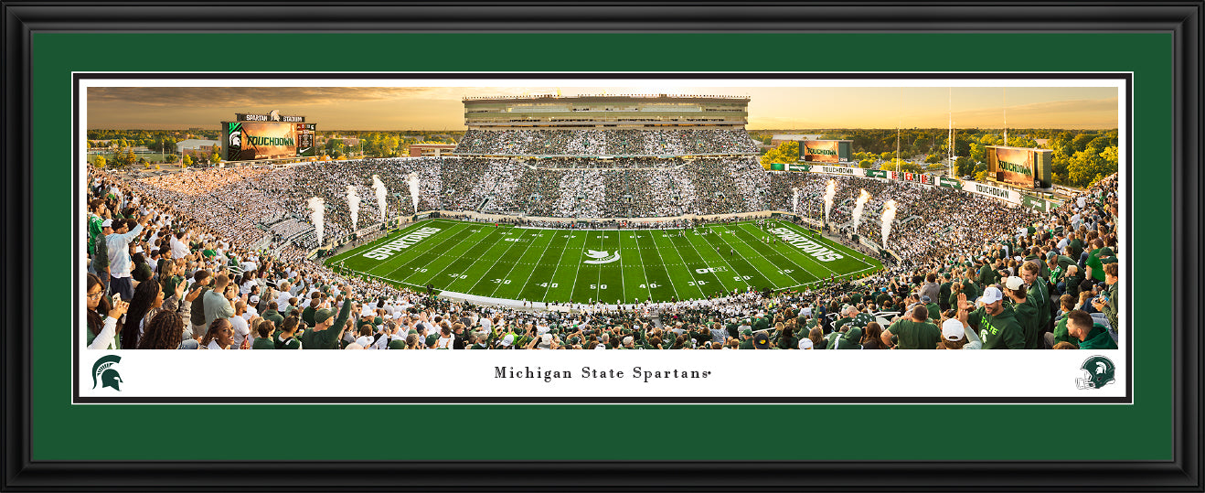 Panorama of the Michigan State Football team going head-to-head with the Western Michigan Broncos. The panorama has a green and white border and is framed with a black deluxe frame. This product measures to 44 inches by 18 inches.