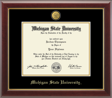 Framed Michigan State University diploma in a dark wood frame with a gold inner edge. The matte is black with a gold inner border surrounding the diploma. Michigan State Seal is at the top of matte and is gold engraved. 'Michigan State University' is inscribed in gold at the bottom of the frame.