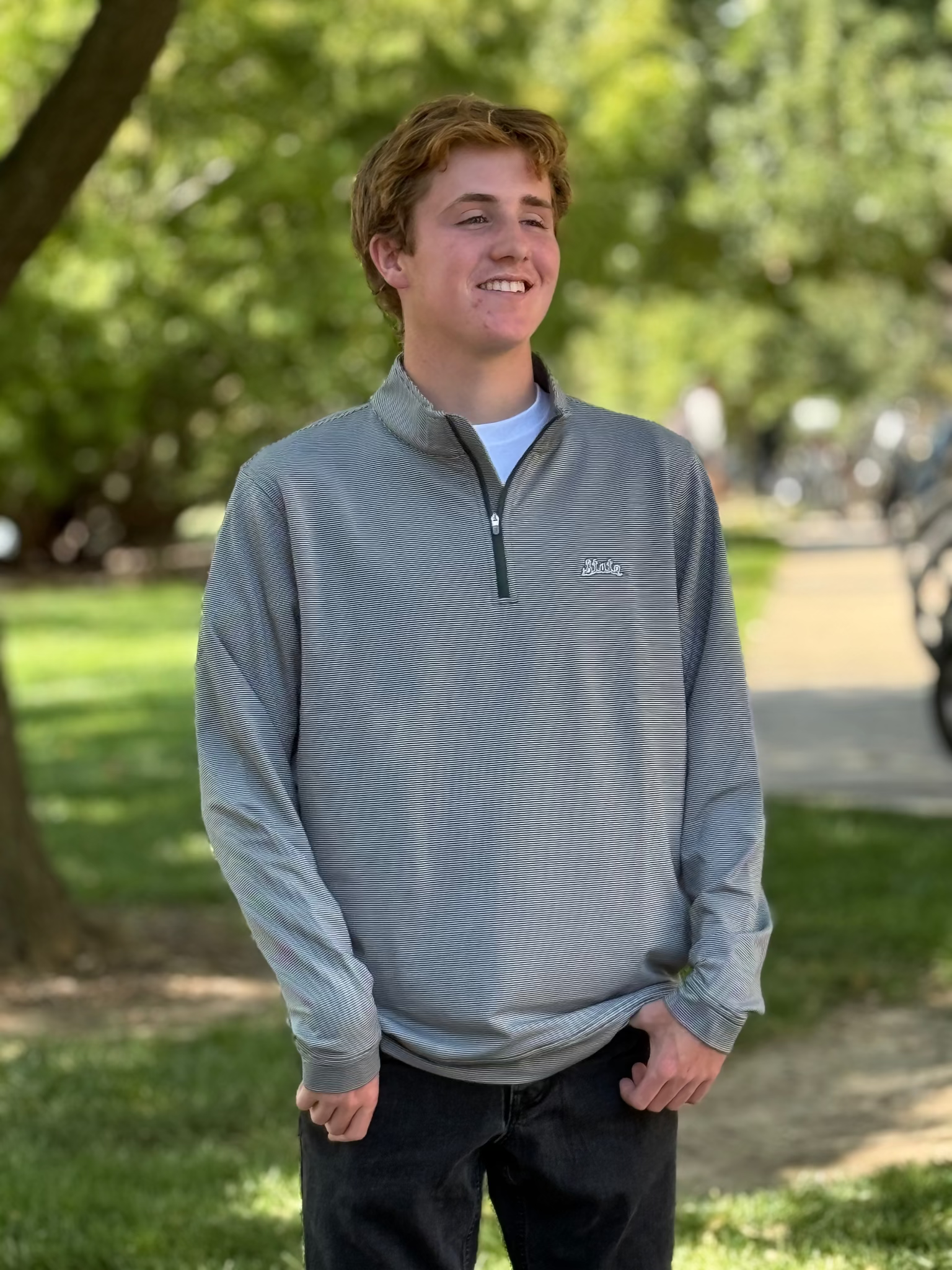 Person wearing a green striped pullover with a State logo in an outdoor setting