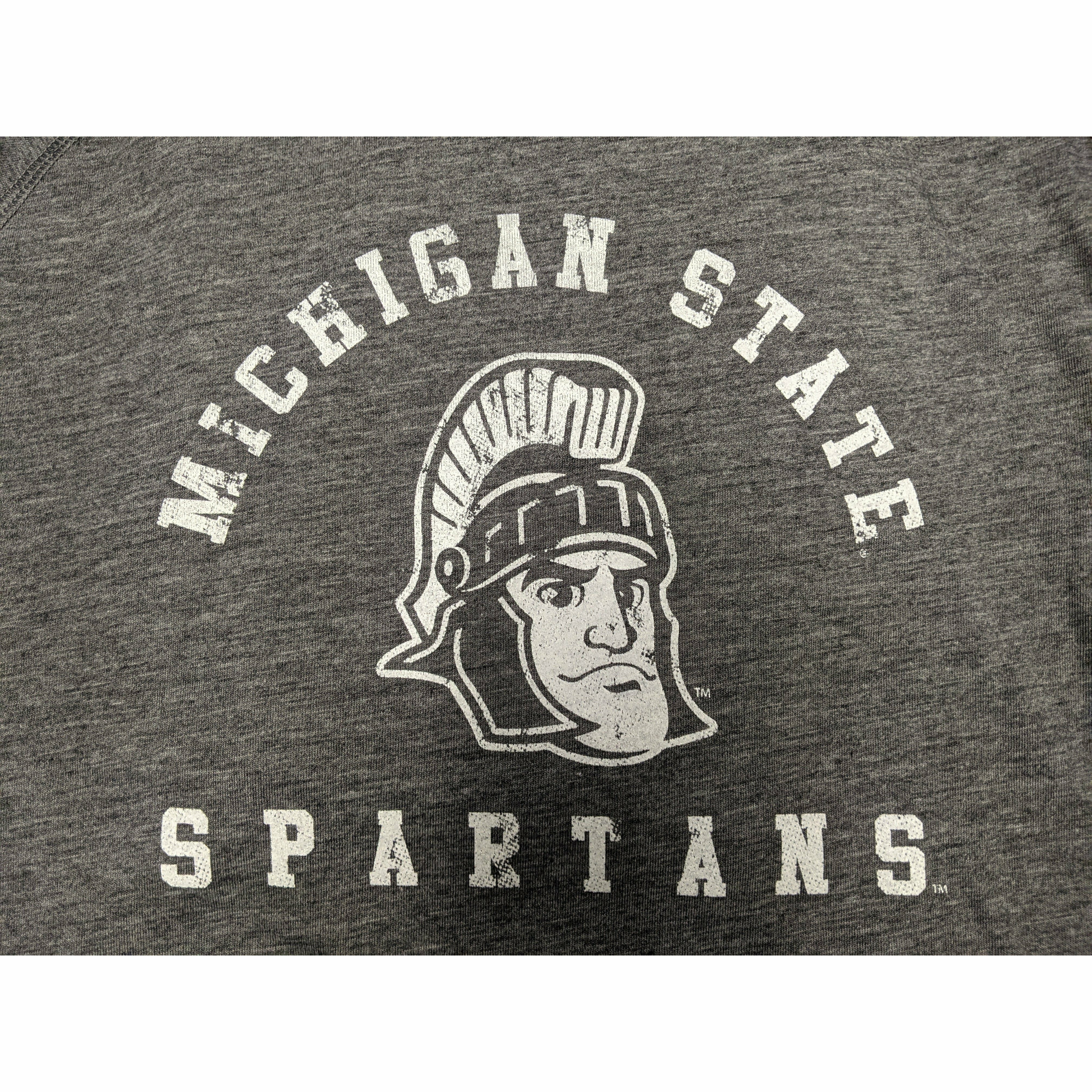 Close-up of a white screen printed rendition of Sparty's head is printed between arched text reading Michigan State and a straight line of text reading Spartans.