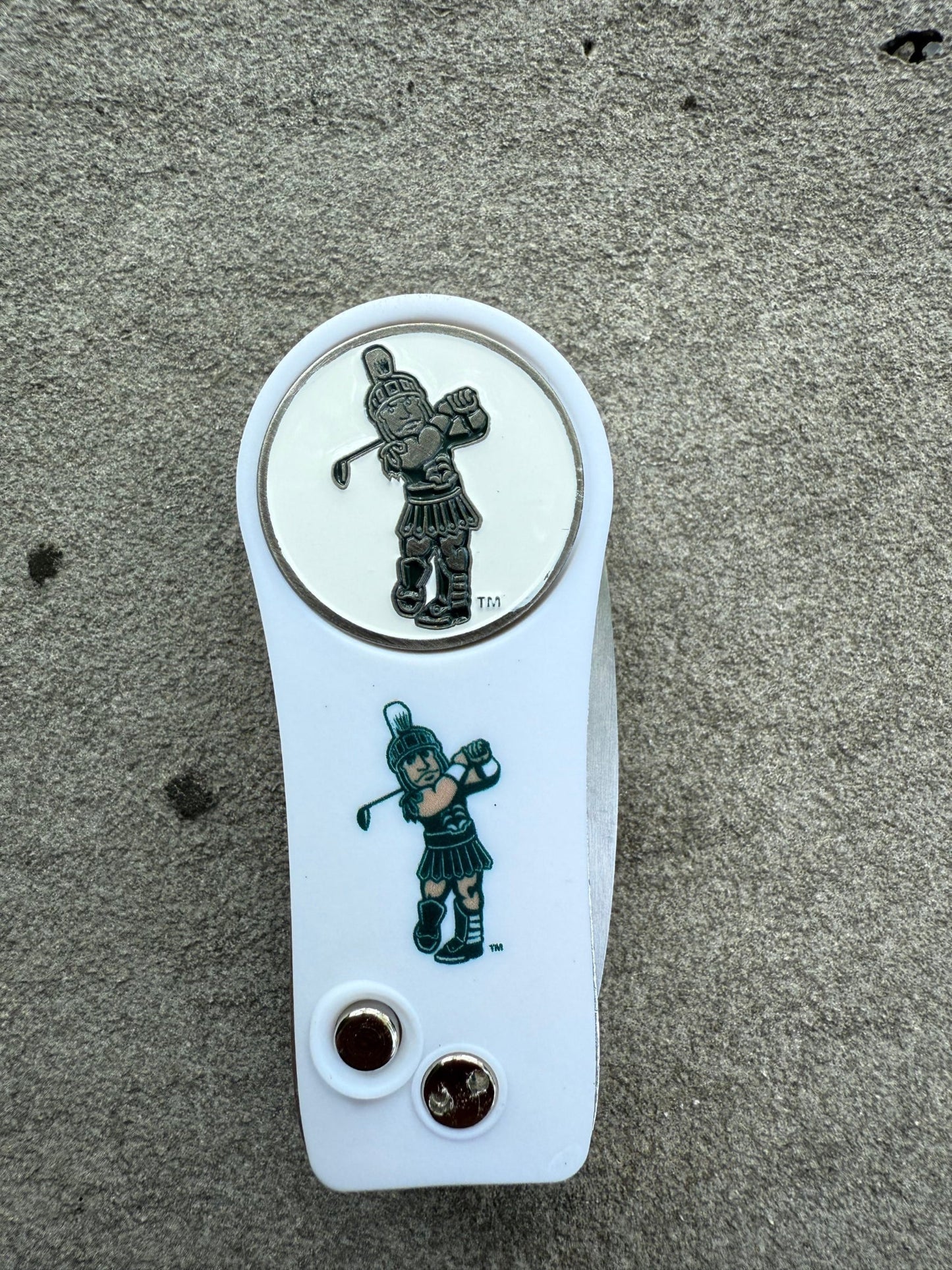 Front side of the white divot tool and magnetic ball marker, both the divot tool and ball marker have the Golf Sparty logo printed on them, and the divot tool has two silver buttons on the bottom.