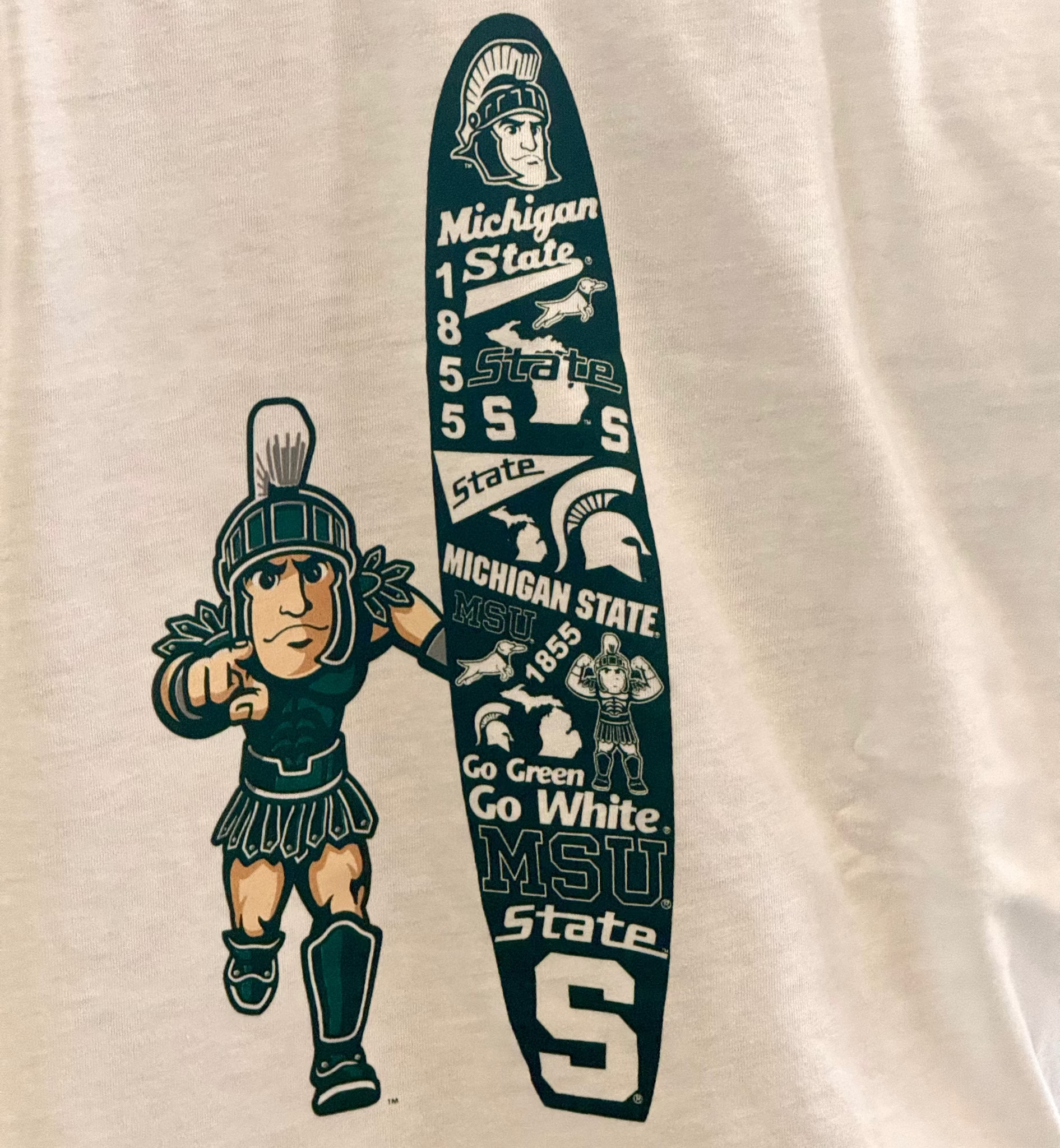 Close up of a screen printed graphic of the Running Sparty logo with a green surf board that has various Michigan State University themed text and logos.