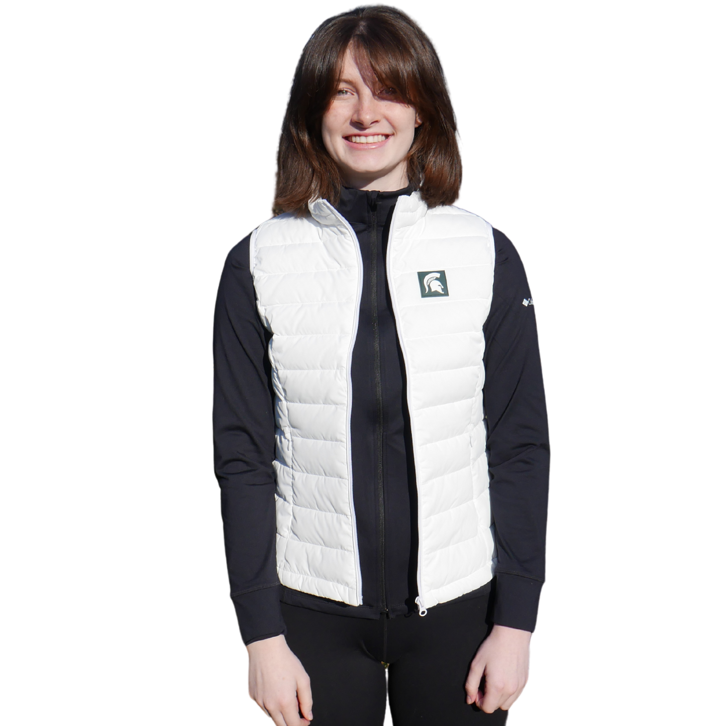 Woman facing forward wearing a white puffer vest that has a small green box with a white Spartan Helmet in it at left chest.