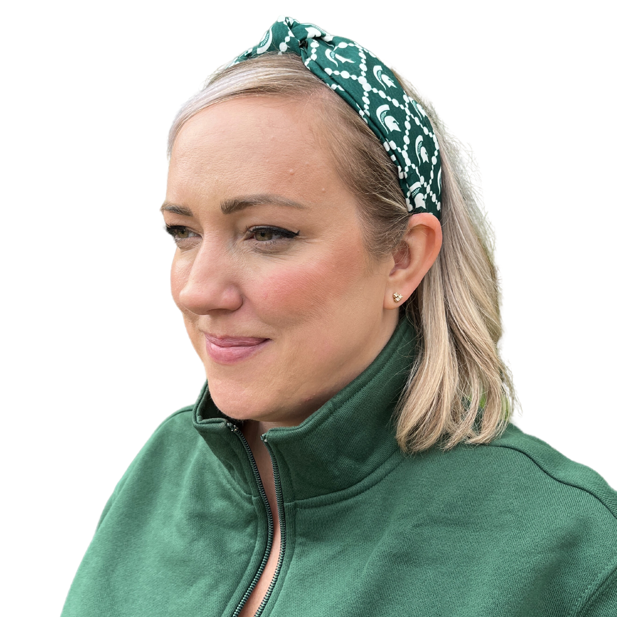 A person with blonde, shoulder-length hair wearing a green and white headband with sublimated Spartan helmet design with white dots linked in diamond shapes around the helmets.