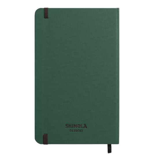 Back of hard linen green notebook with "Shinola Detroit" branding on a plain green back cover.