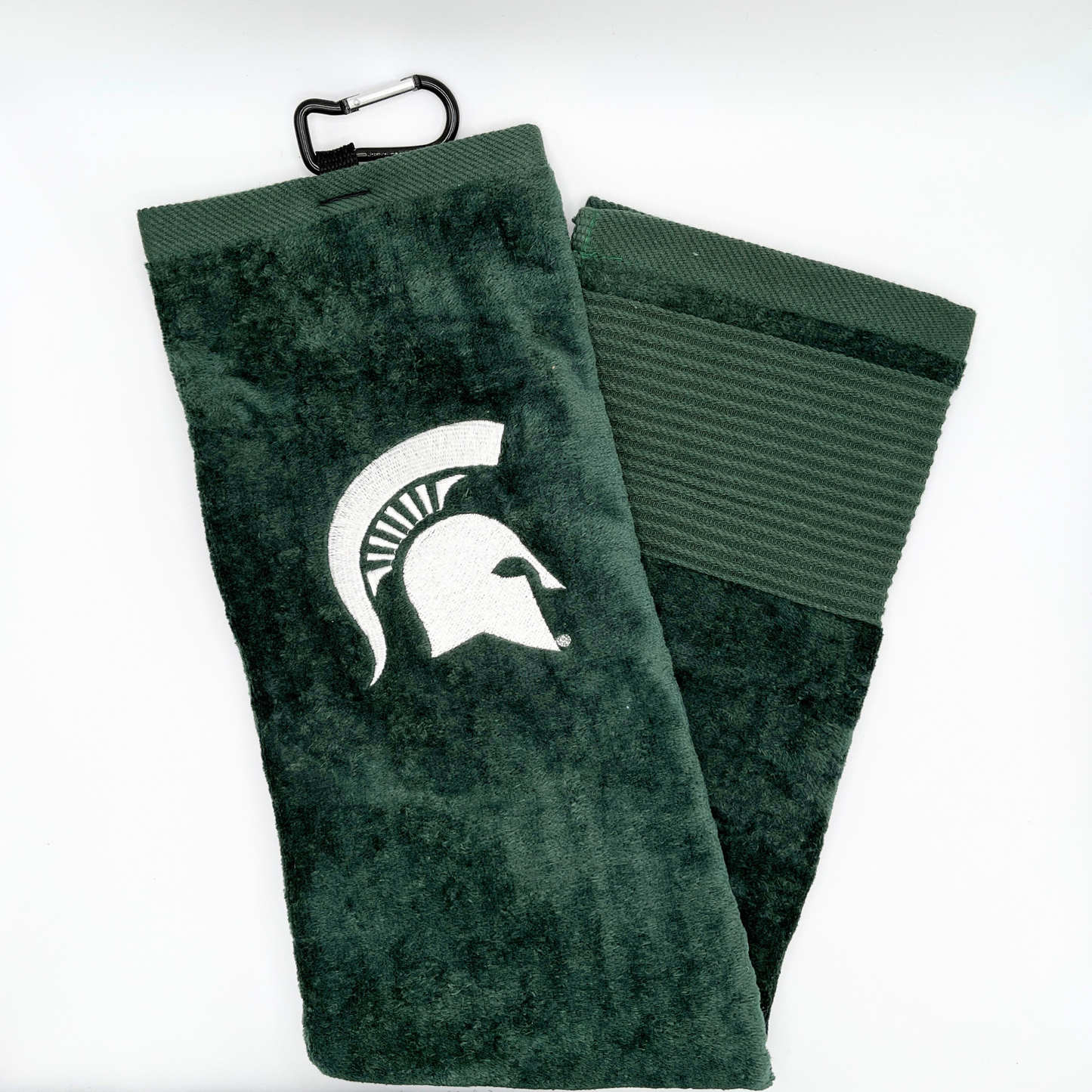 A dark green golf towel with a black clip at the top to attach to golf bags. On the towel is a white Spartan Helmet logo.