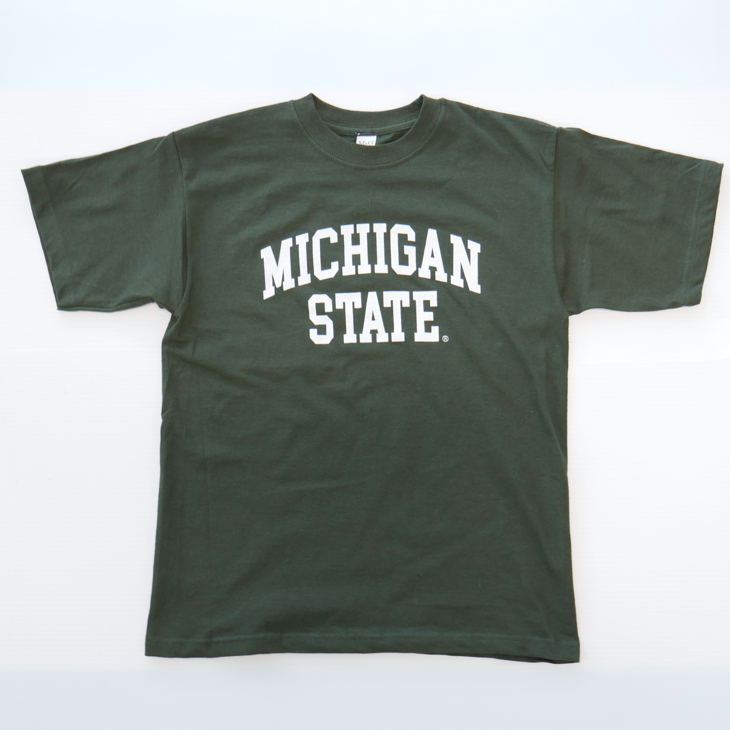 A dark green youth-sized tee shirt with a curved white wordmark that reads "Michigan State" in the center of the T-shirt.