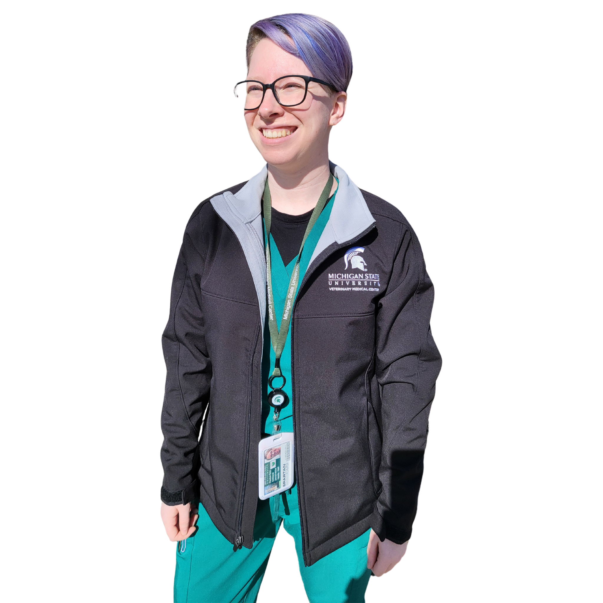 A woman in green scrubs wearing a black full-zip jacket. The upper left chest is embroidered with a Veterinary Medical Center logo in white.