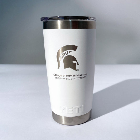A white, 20 ounce beverage tumbler with a silver etched Spartan Helmet logo and the words "Michigan State University College of Human Medicine" below it.