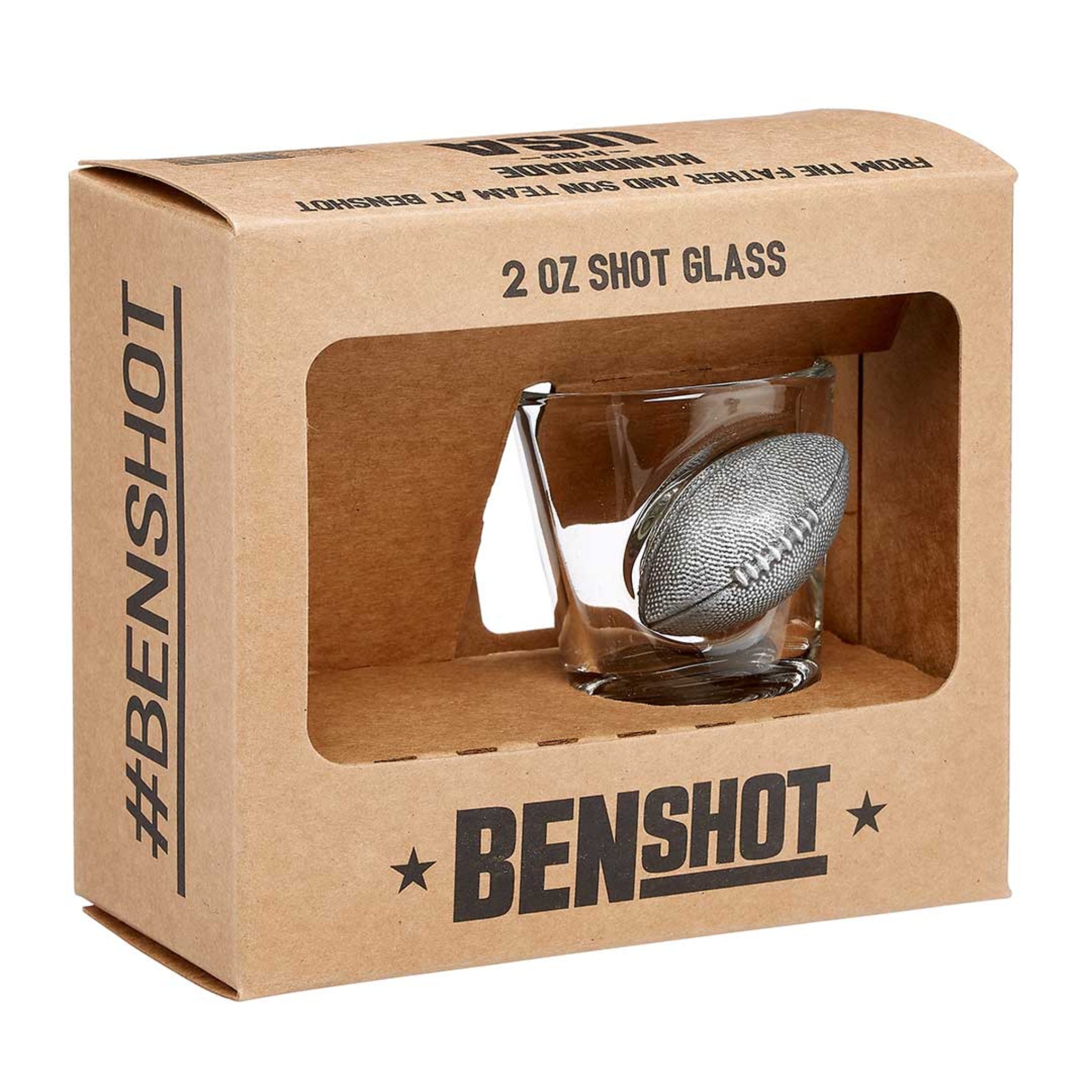 A packaged BenShot football shot glass in a brown kraft box with a cut-out window displaying the shot glass inside. The box features the BenShot logo and has a frosted Spartan helmet logo on the other side.