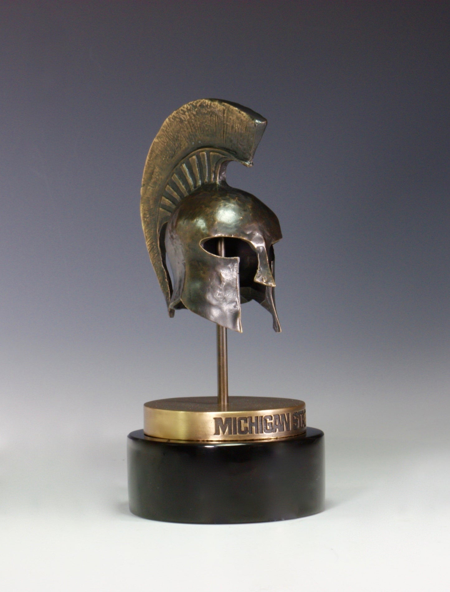 A bronze Spartan Helmet statue on a black base.