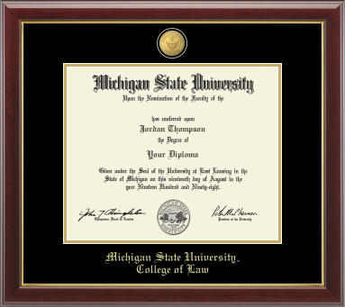 The diploma is displayed in a dark wood frame with a black matte and gold trim, and includes signatures from university officials. In gold and cursive writing is Michigan State University. Below in gold cursive letters is College of Law.