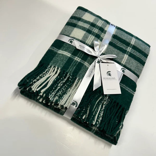 Folded green and white plaid wool throw with fringe, tied with a white Michigan State University ribbon and tag.