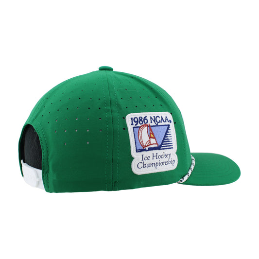 Side view on a bright green hat with a white plastic adjustable clasp at the back and a 1986 NCAA Ice Hockey Championship patch on the right side of the hat. Along the bill of the hat is a white and green thin rope. 