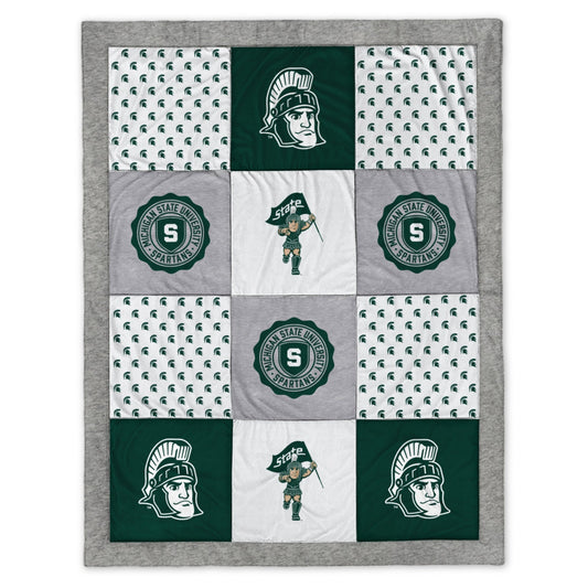 A patchwork blanket of gray, green, and white fabric with various MSU and Sparty motifs.