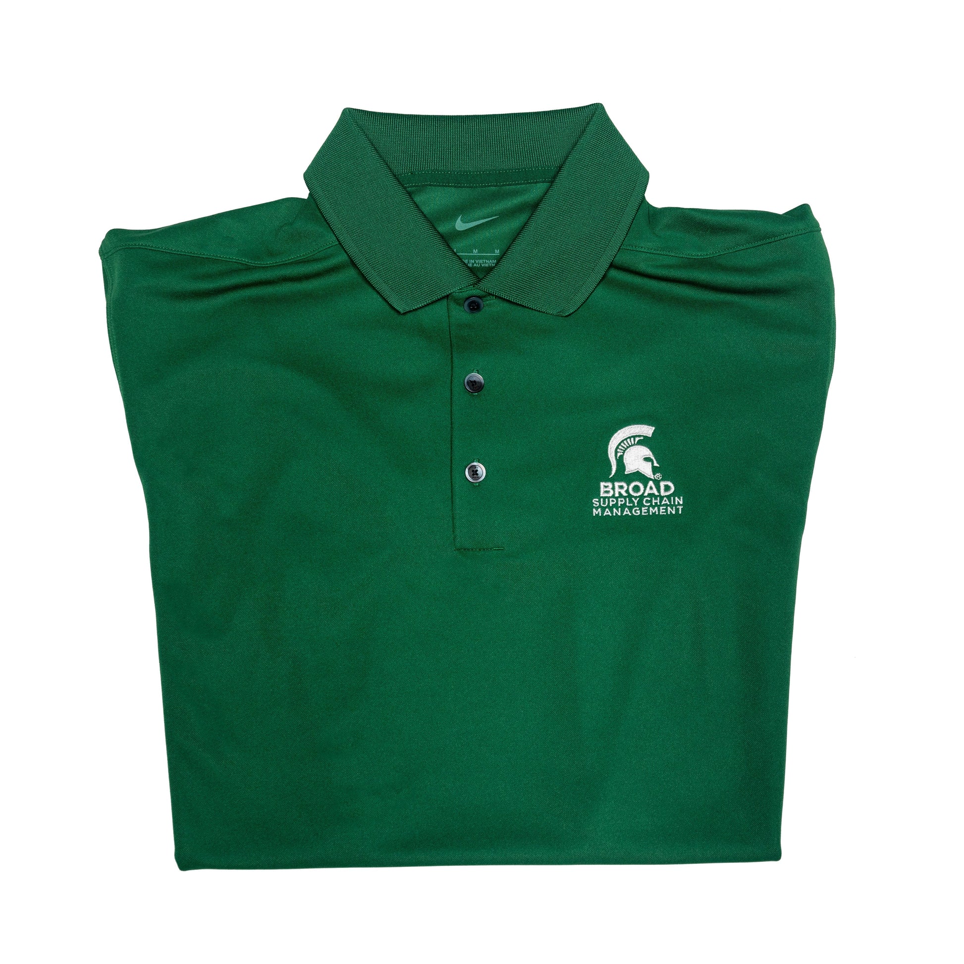 Close-up of a folded green Nike collared polo with three buttons. A white Spartan Helmet over the Broad Supply Chain Management logo is embroidered on the left upper chest.