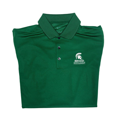 Close-up of a folded green Nike collared polo with three buttons. A white Spartan Helmet over the Broad Supply Chain Management logo is embroidered on the left upper chest.