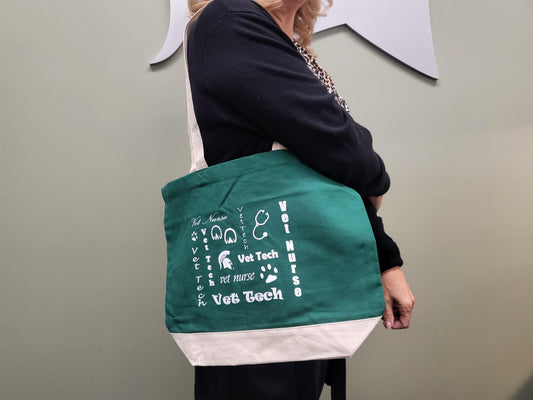Person with a green canvas tote bag with white straps, a white bottom section, and white "Vet Tech" text and graphics related to veterinary technology and veterinary nursing.