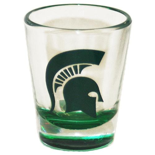 A clear shot glass with a green bottom featuring a green Spartan Helmet logo.