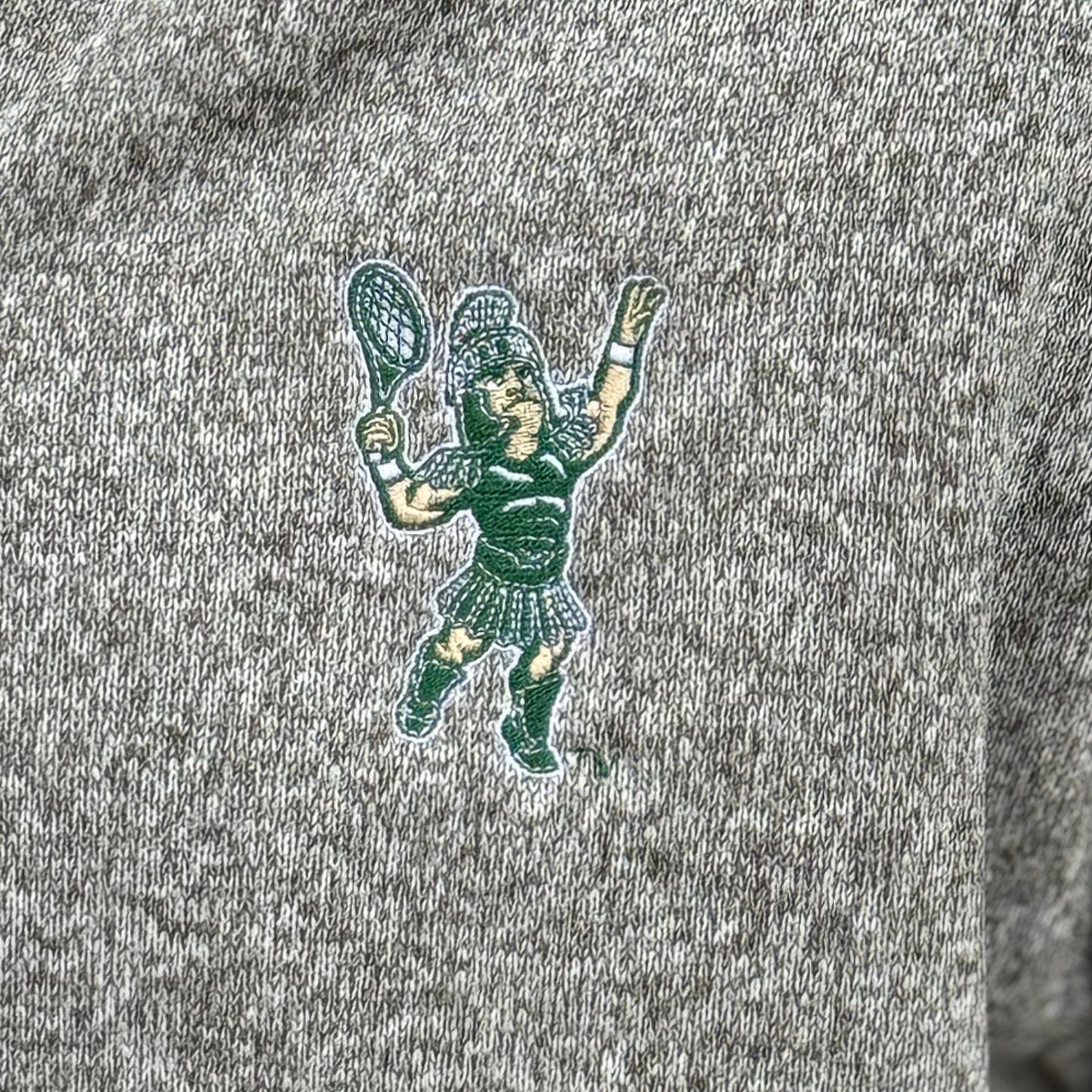 Close up of the embroidered Sparty playing tennis on the upper left chest of the full zip jacket.