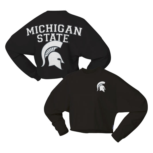 Front and back images of the black long-sleeve cropped t-shirt.  The back features 'MICHIGAN STATE' in white block letters above a large white Spartan helmet logo. The front features a left side white Spartan helmet. 