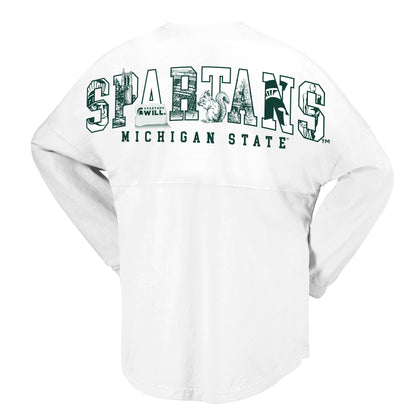 Back view of a white Michigan State Spartans long-sleeve sweatshirt featuring oversized “SPARTANS” lettering across the upper back in green and white. Each letter contains Michigan State-themed graphics, including Beaumont Tower, the Spartan helmet logo, a squirrel, a “Spartans Will.” design, and campus-inspired imagery. “MICHIGAN STATE” appears below the graphic in green block lettering. Garment shown on a light gray background