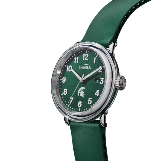 Green Shinola watch with green face and strap featuring white numbers and a white Spartan Helmet logo. Stainless-steel watch casing. 