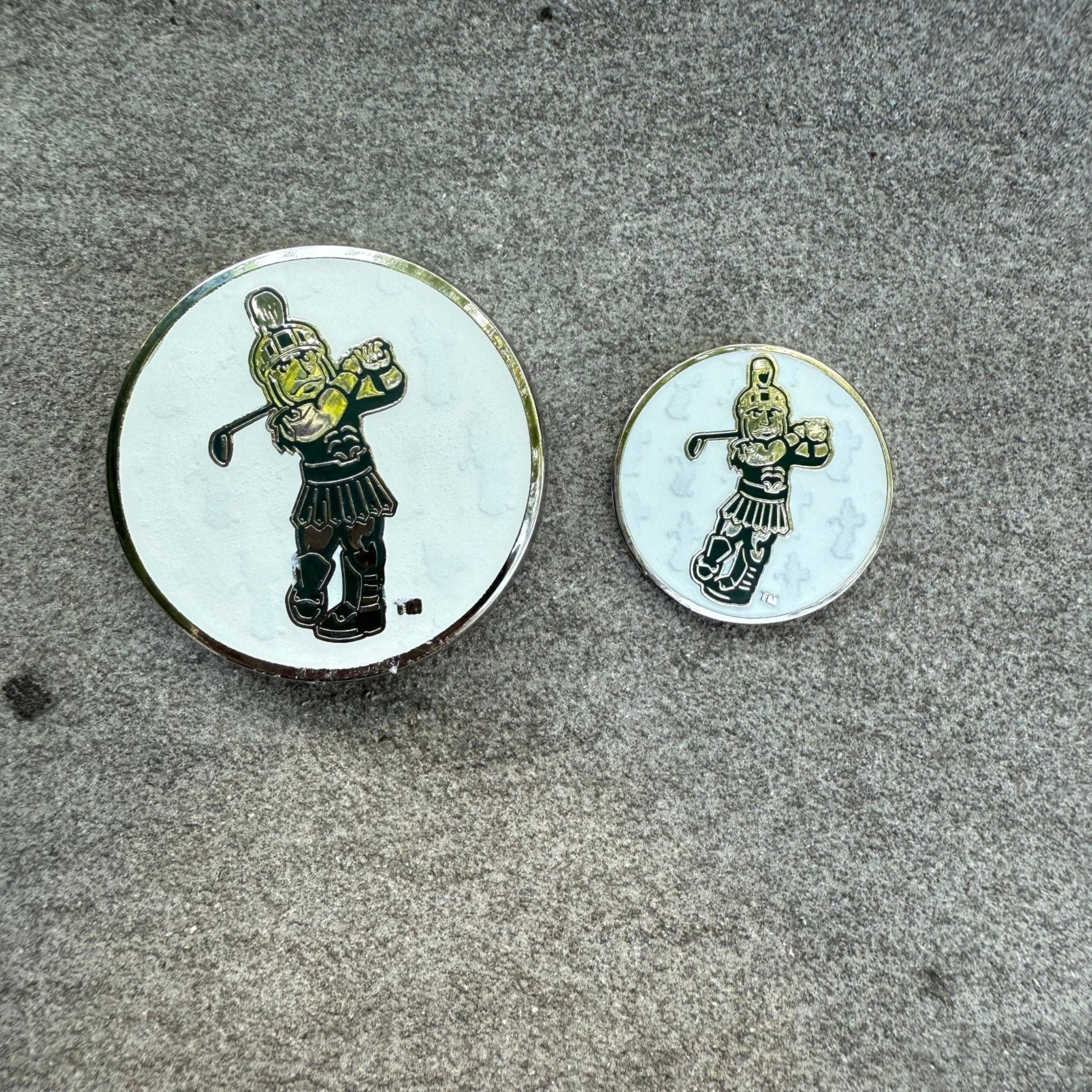 Two round pins with Golf Sparty designs with white background of pins. 