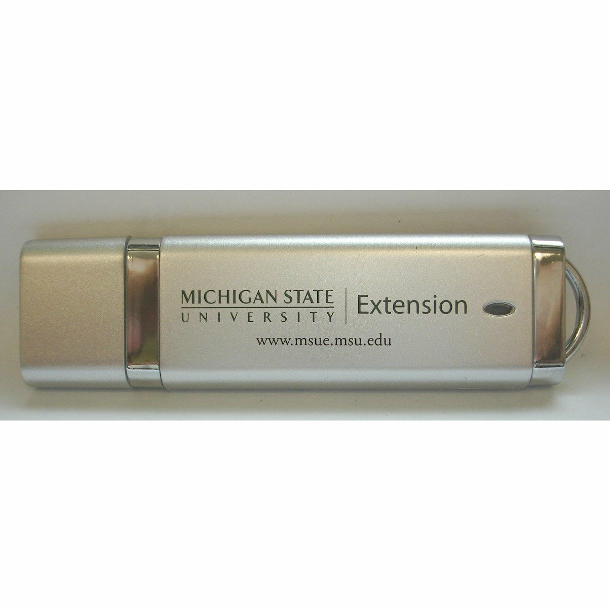A silver, 8 gigabyte flash drive with the MSU extension signature and website address on the side, both in the spartan green colorway.