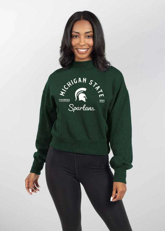 Dark green sweatshirt featuring arched 'MICHIGAN STATE' text above a Spartan helmet logo, with 'Spartans' in cursive below and 'FOUNDED 1855' on either side of the logo.