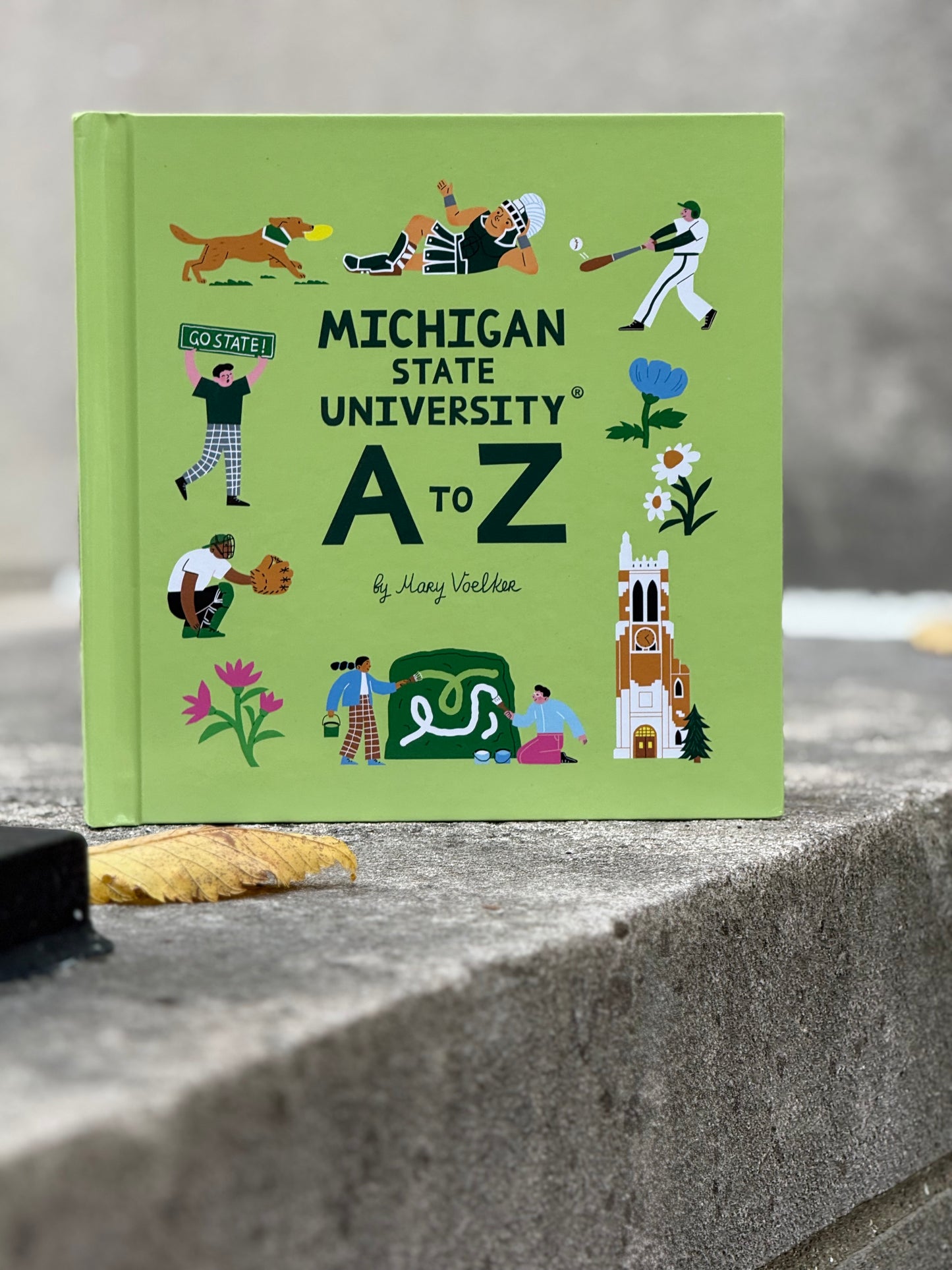 Light green book titled 'Michigan State University A to Z' sitting on a concrete surface