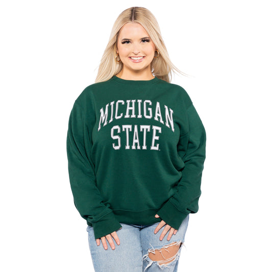 Person in green 'Michigan State' sweatshirt and ripped jeans.